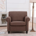 Sillón tapizado color café con brazos enrollados y tachuelas decorativas